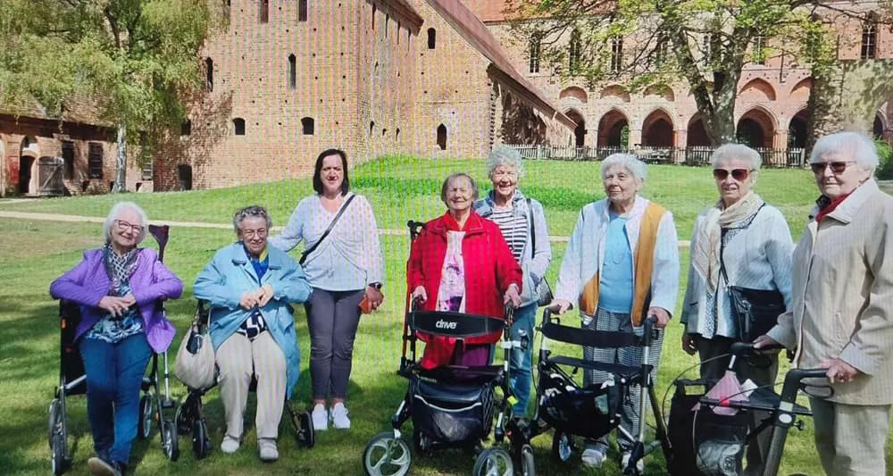 Klienten und eine Mitarbeiterin auf der Wiese vor dem Kloster Chorin