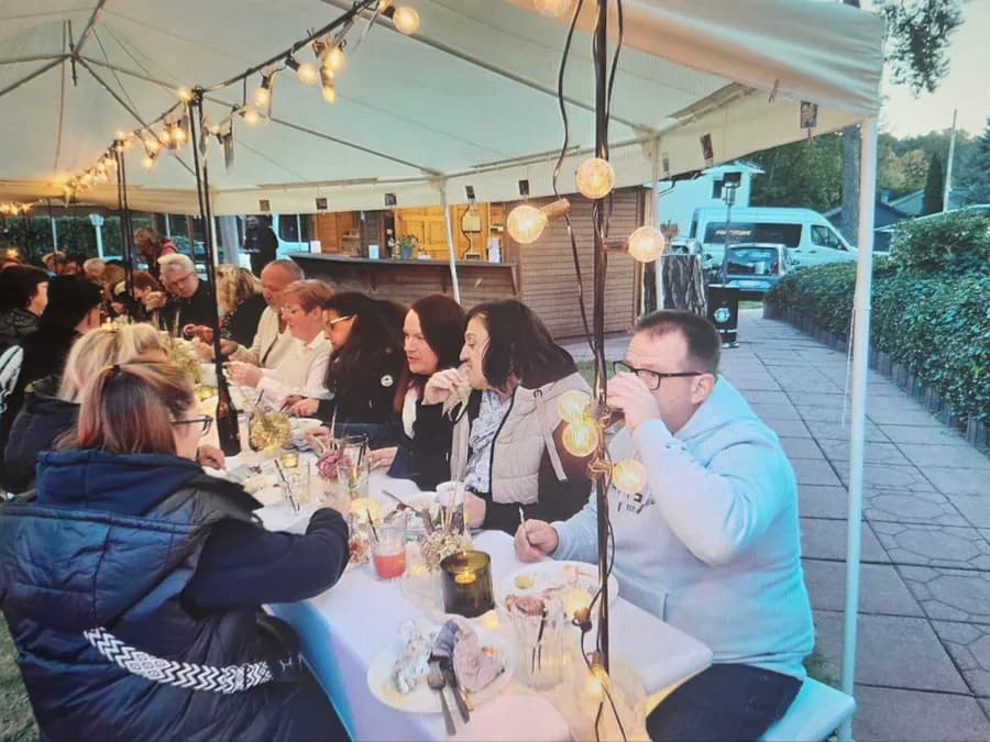 Gäste beim gemeinsamen Abendessen an der Tafel im Festzelt