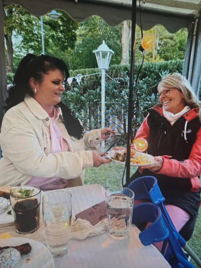 Zwei Gäste reichen sich beim Essen im Zelt einen Teller