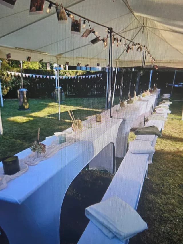 Lange gedeckte Tafel im Festzelt mit Lichterkette und Fotos
