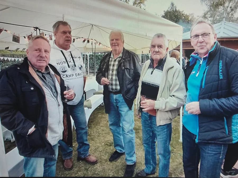 Fünf Gäste stehen mit Getränken im Festzelt zusammen