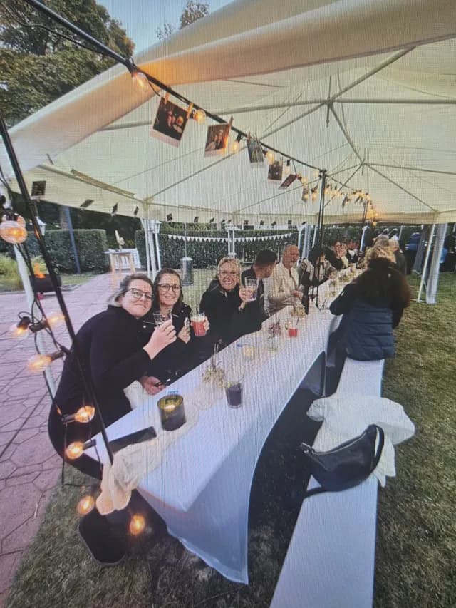Gäste stoßen an der langen Tafel mit ihren Getränken an