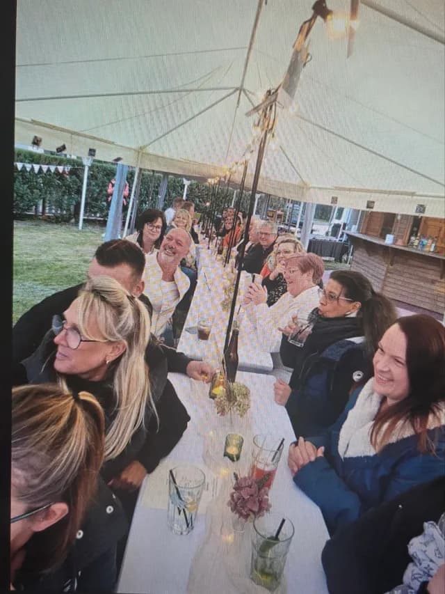 Gäste sitzen an der langen Tafel im Festzelt