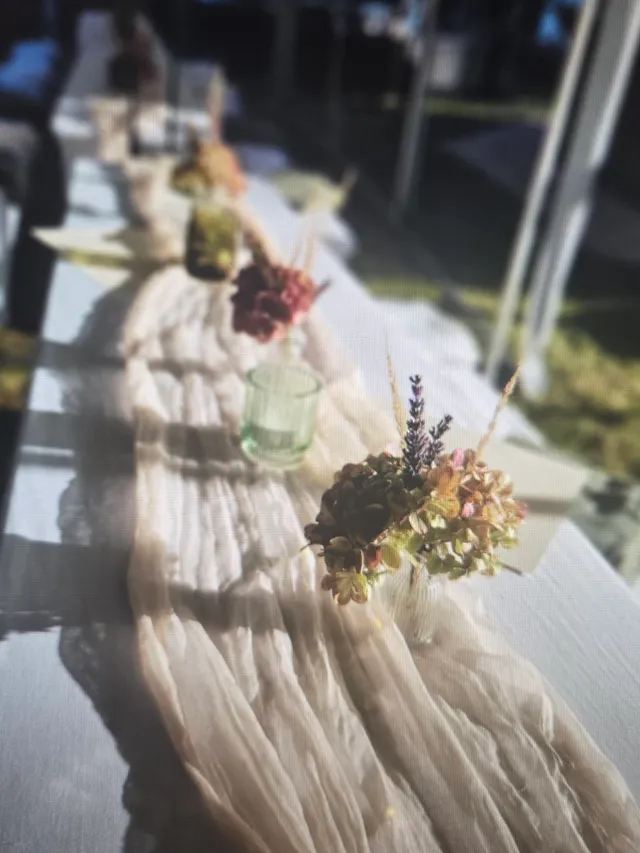 Festlich gedeckte Tafel mit Blumenschmuck und Stoffläufer im Festzelt