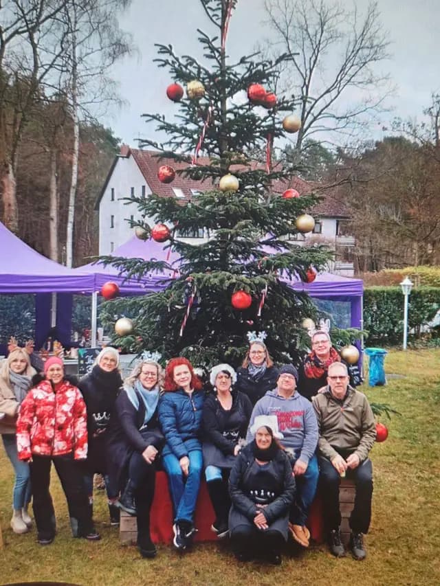 Das Team vor dem geschmückten Weihnachtsbaum im Garten