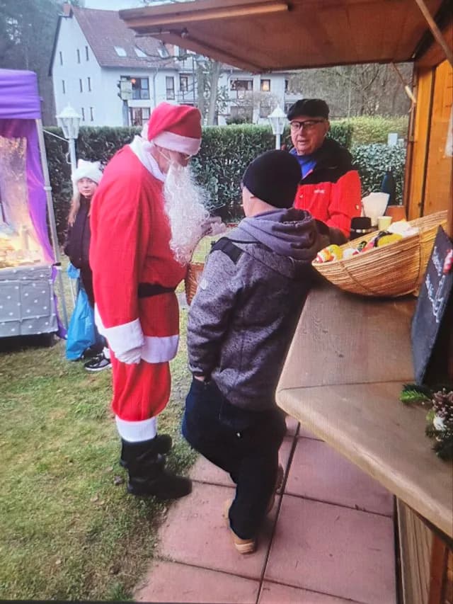 Der Weihnachtsmann im Gespräch mit einem Gast am Holzstand